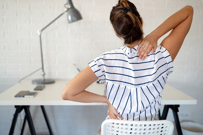 Woman in the office over worked with back pain from sitting all day