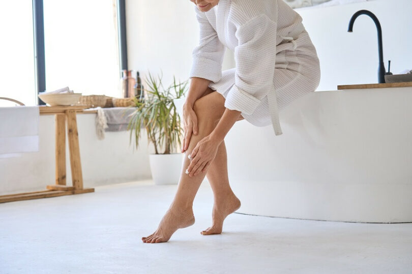 Middle aged woman applying cein cream on legs